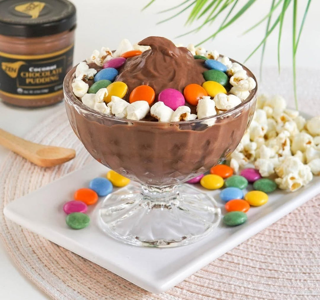Zen Chocolate Coconut Pudding in a glass bowl, topped with popcorn and colorful candies. Served with a side of popcorn and candies.